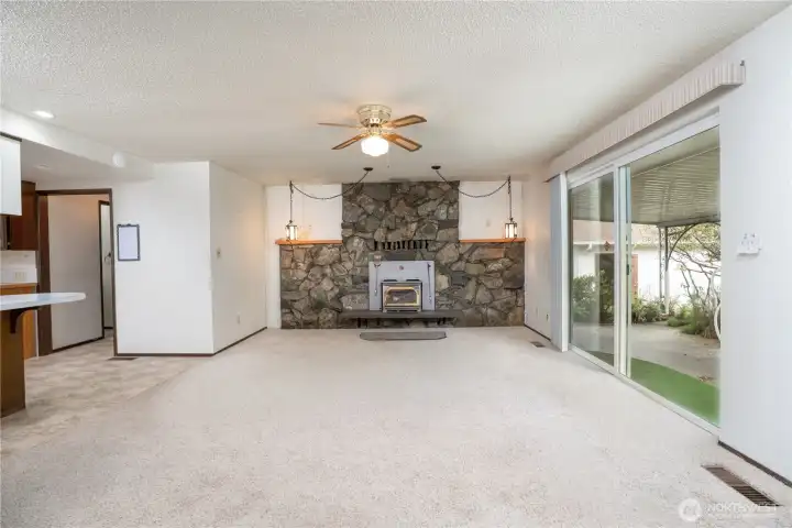 The living room features a stone wood burning fireplace with insert to keep you toast warm and access to the covered patio through the sliding glass door, on the left is the kitchen.