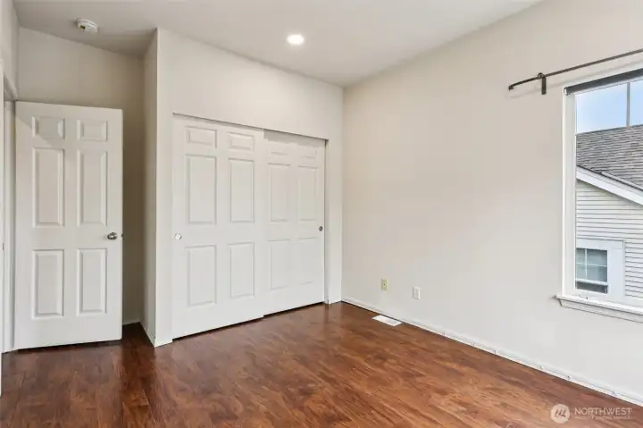 Bright and versatile second bedroom featuring warm flooring, ample closet space, and natural light—perfect for guests, a home office, or whatever fits your lifestyle.