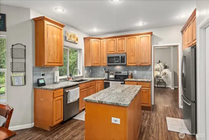 Granite surfaces, stainless appliances, and a central island create a functional kitchen designed for both cooking and conversation.