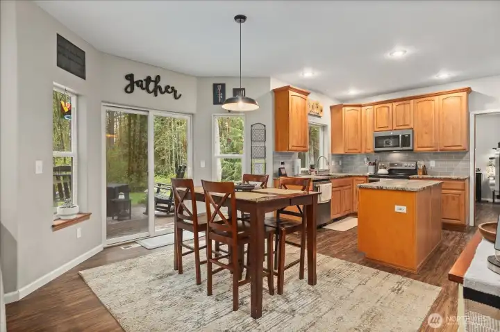 The dining area is surrounded by natural light, with direct access to the outdoor deck for easy indoor-outdoor living.