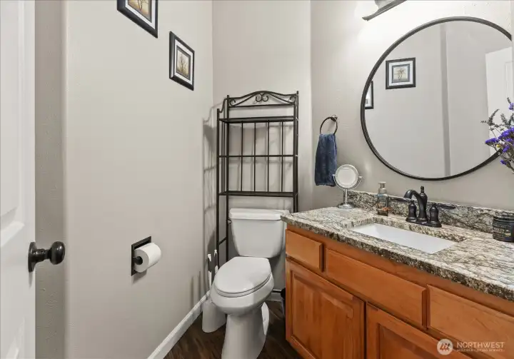 A main-level powder room features granite countertops and warm cabinetry, offering both style and everyday convenience.