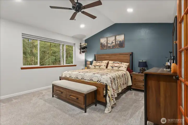 A spacious primary suite with vaulted ceilings and a calming accent wall creates a comfortable retreat at the end of the day.