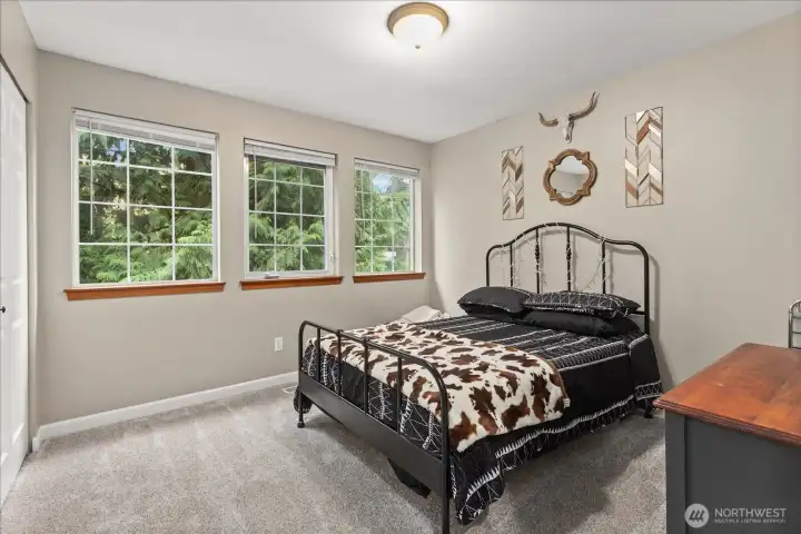Bright bedroom with multiple windows and serene views of the surrounding greenery.