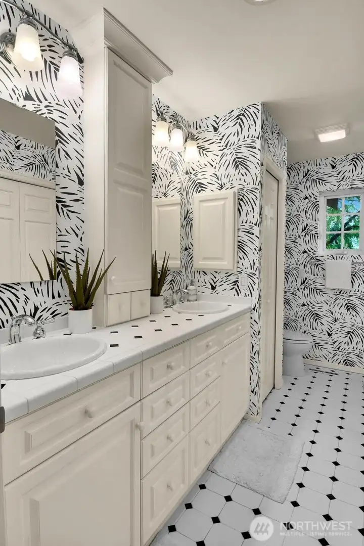 The hall guest bath with tile floor, double sinks, updated lighting.