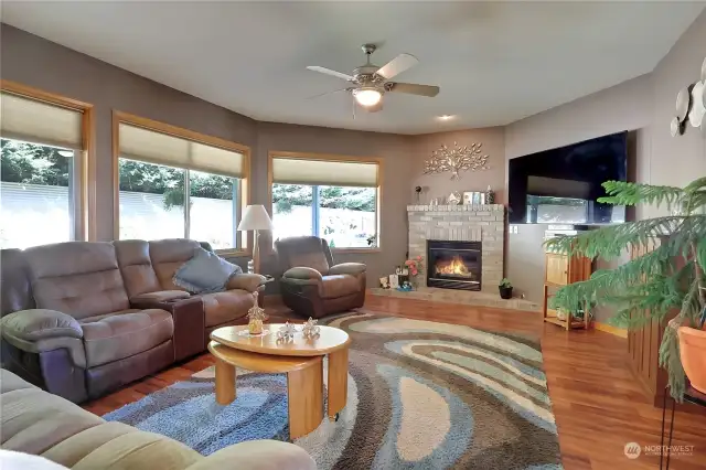 Living room features a gas fireplace and natural light from the large pictures windows