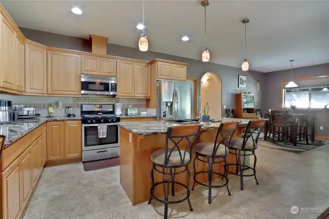 Modern kitchen with island, featuring stainless steel appliances, granite countertops, custom cabinets and pendant lights.