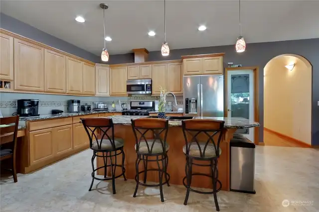 Alternative view of the kitchen showcasing island and walk-in pantry with sensor lighting and ample storage space.