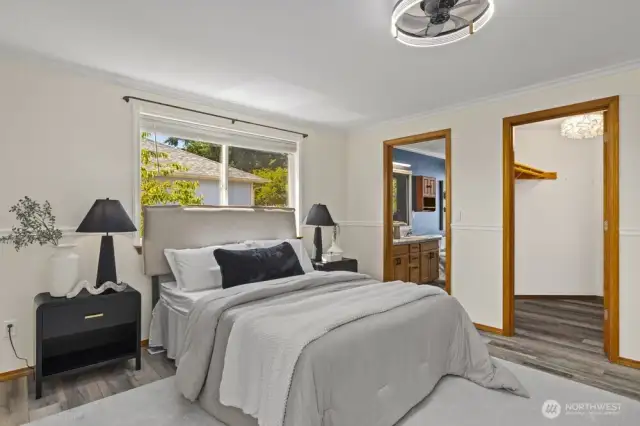 The door to the left leads to the primary bathroom, and the door to the right leads to the walk-in closet with hanging space and shelves on both long walls.