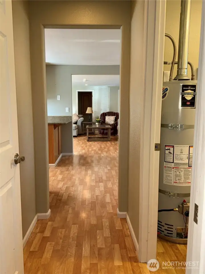 View looking north across the home when exiting the primary ensuite.  Laundry room is on the right.  Water heater is located there.  Washer and dryer remain.
