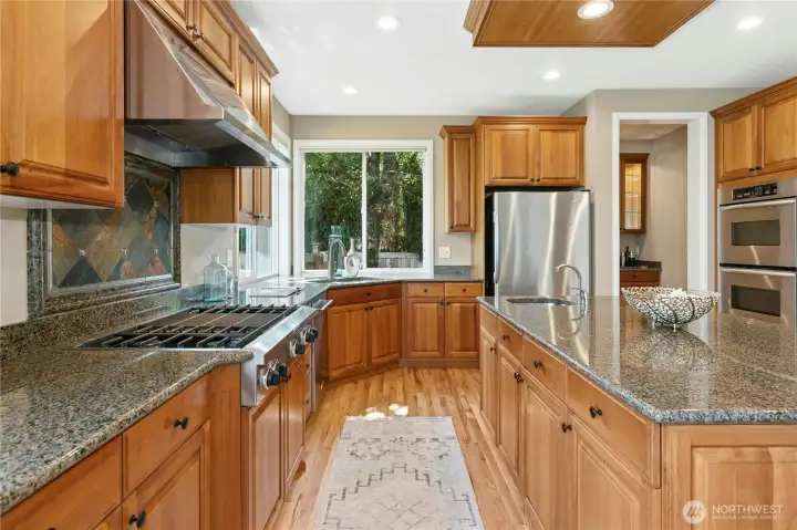Light pours in, highlighting granite countertops and raised panel Alder custom cabinetry.
