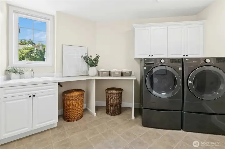 Bright and functional, the laundry room features stylish cabinetry, a folding station, and a separate storage nook for easy access.