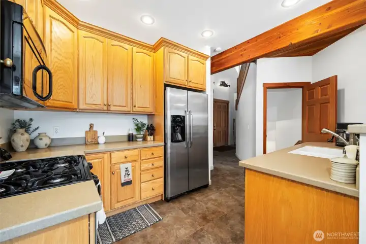 The kitchen has a gas range and solid wood cabinets. The open doorway leads you to the basement.
