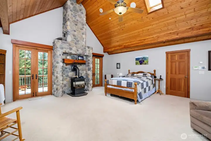 The primary suite is very spacious and has a gas freestanding stove. There is a private deck with French doors that overlooks the large lawn. The closed door leads to one of the 2 large walk-in closets.