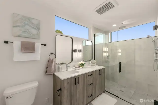 Luxurious bathroom featuring a dual-sink vanity with modern fixtures and a spacious glass-enclosed shower with abundant natural light.