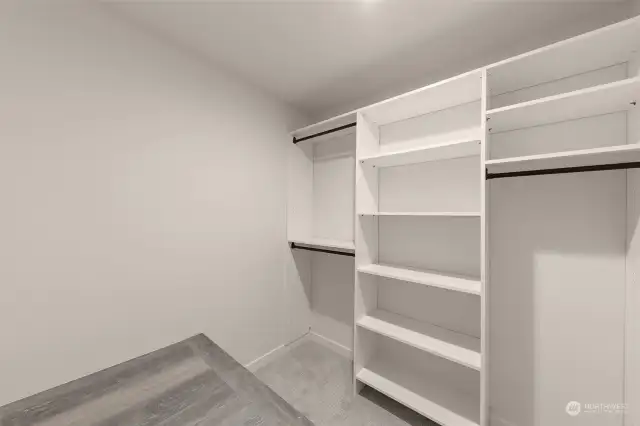 An ample walk-in closet with custom shelving, a pleasant storage space, and a built-seating area.