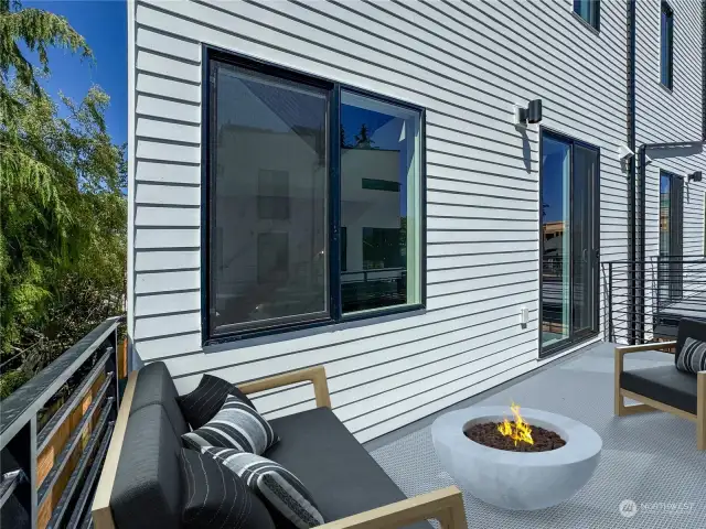 Modern deck with comfortable seating and large windows for seamless indoor-outdoor living.