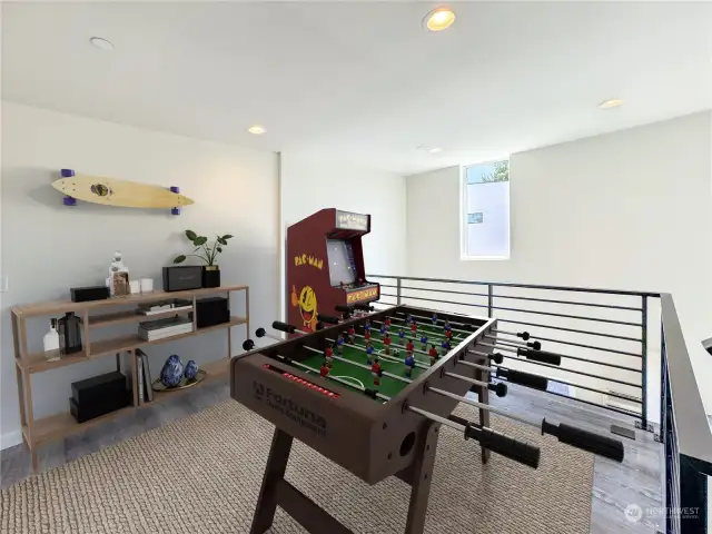 This truly is a versatile floor! This concept features a stylish game room with a foosball table, Pac-Man arcade machine, and modern decor for entertainment.