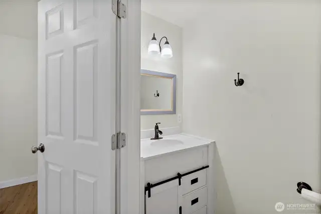 Half bath with updated vanity, bronze fixtures, and a framed mirror for a polished touch.  Located in the primary ensuite.