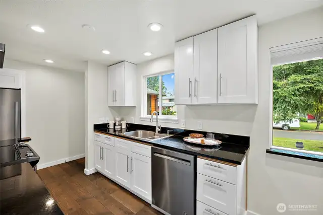 Crisp white cabinets, sleek black counters, and stainless steel appliances make this kitchen feel fresh, functional, and ready for everyday life.