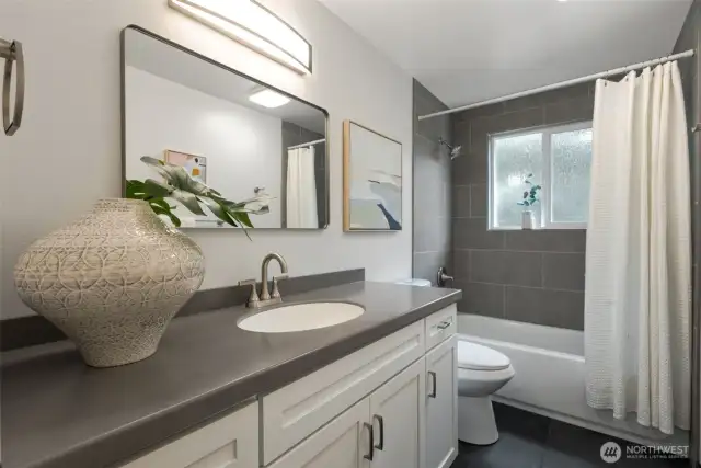 Main floor bathroom with custom cabinets & beautiful tile on the floors and the tub/shower surround.