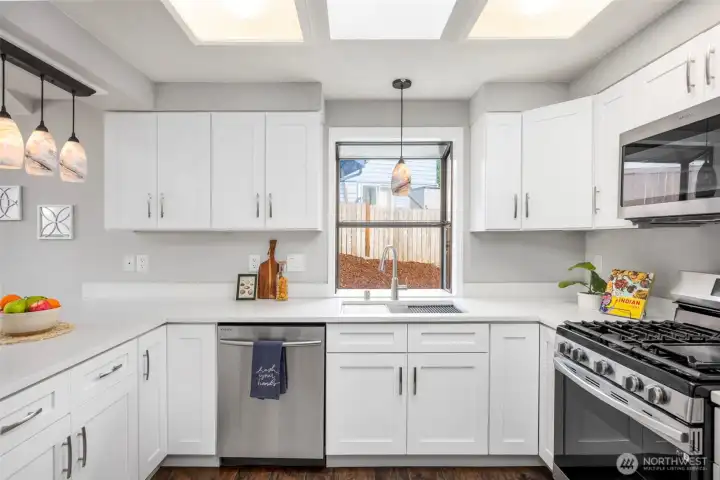 Kitchen with quartz countertops, stainless steal appliances and gas range. Window overlooks outdoor area and firepit.