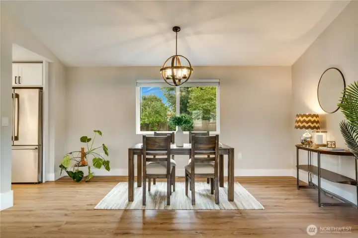 The open living and dining space features the new flooring, trim, blinds, lighting, and fresh paint found throughout the home.