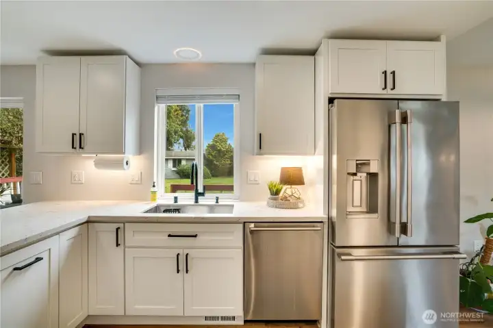 This renovated kitchen is all new. Features shown here include bright quartz counters, a new undermount sink wired for a garbage disposal, and just a few of the soft-close cabinets including a pull-out for the garbage bin.