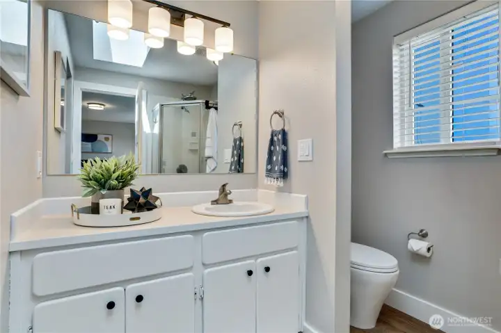 This private 3/4 bath attached to the primary suite features fresh paint, new flooring, trim, light fixtures, and shower head.