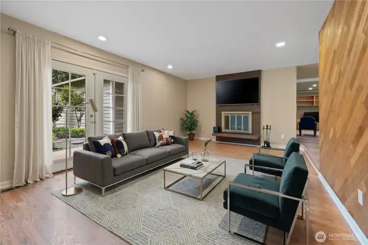 Spacious living room with wood-burning fireplace and French doors leading to the patio. (digitally staged)