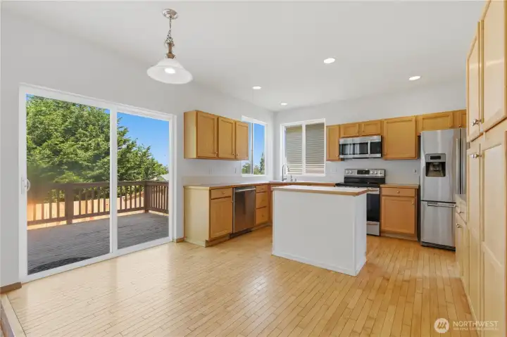 A chandelier hangs over an area great for casual dinning. The sliding door leads to the back deck and a great position for the outdoor bbq enthusiast. Large cabinet pantry and additional counter space is shown to the right.
