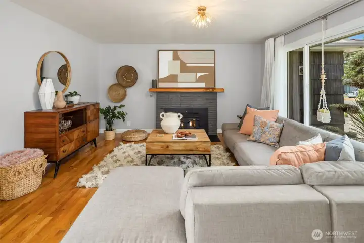 Spacious living room with fireplace, modern lighting and large window and lots of natural light.