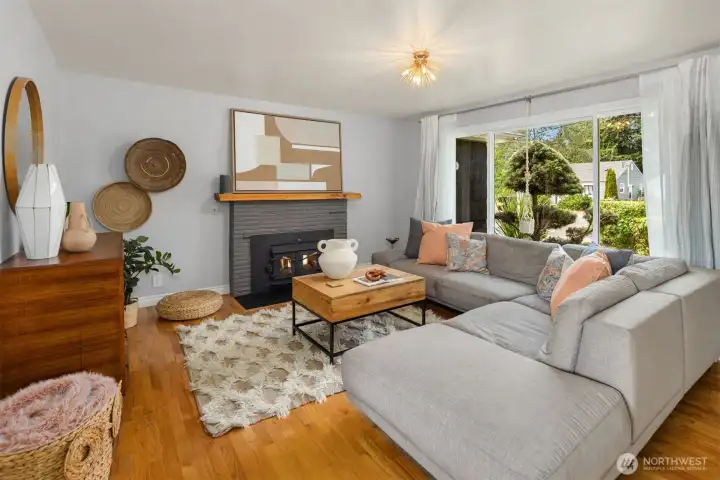 Spacious living room easily holds an oversized sofa and is anchored by a wood burning fireplace.