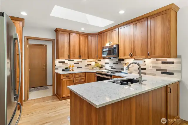 Beautiful bright kitchen with gorgeous Pecan cabinetry, stainless steel appliances, quartz counters and tile backsplash.