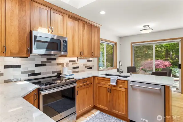 Beautiful bright kitchen & dining nook with gorgeous Pecan cabinetry, stainless steel appliances, quartz counters and tile backsplash.