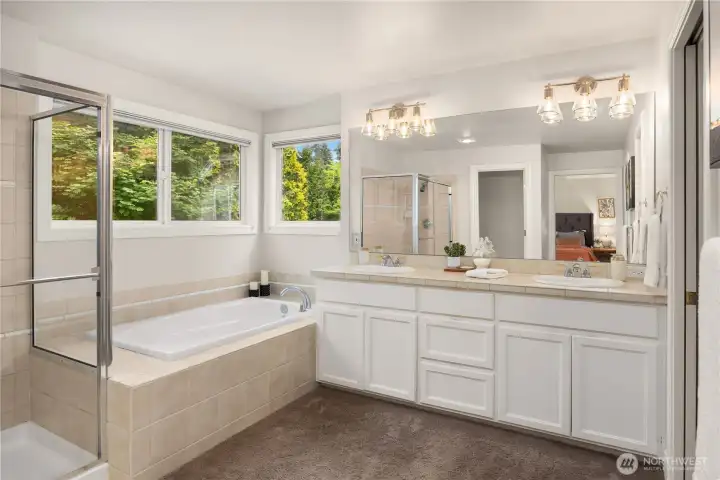 Elegant primary bathroom includes a soaking tub, separate shower, water closet, and dual sinks with generous storage.