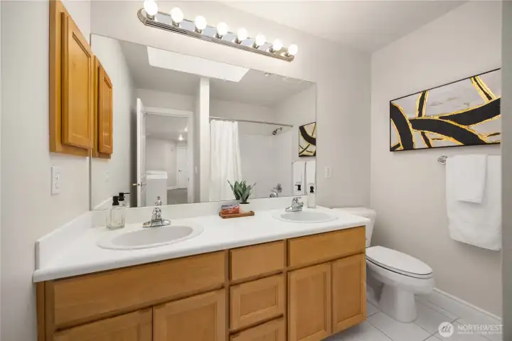 Full upstairs bathroom offers dual vanity and natural light from a skylight.