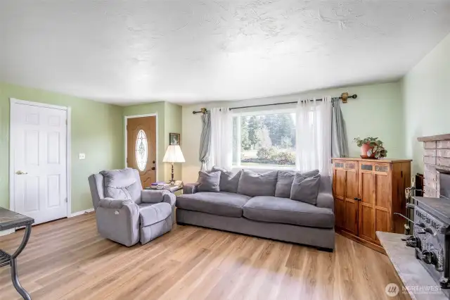Living Room Overflowing With Natural Light Onto Brand New Floors Accompanied By A Wood Burning Fireplace Insert For The Cold Days