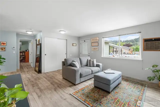 Another view of the living room. To the left is the kitchen and dining room. Straight ahead is the primary bedroom. Just before the door to the primary to the right is the laundry room and the the door to the garage.