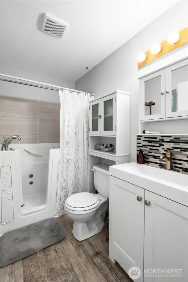 The guest bathroom features an ADA compliant tub with shower, new exhaust fan, and laminate flooring.