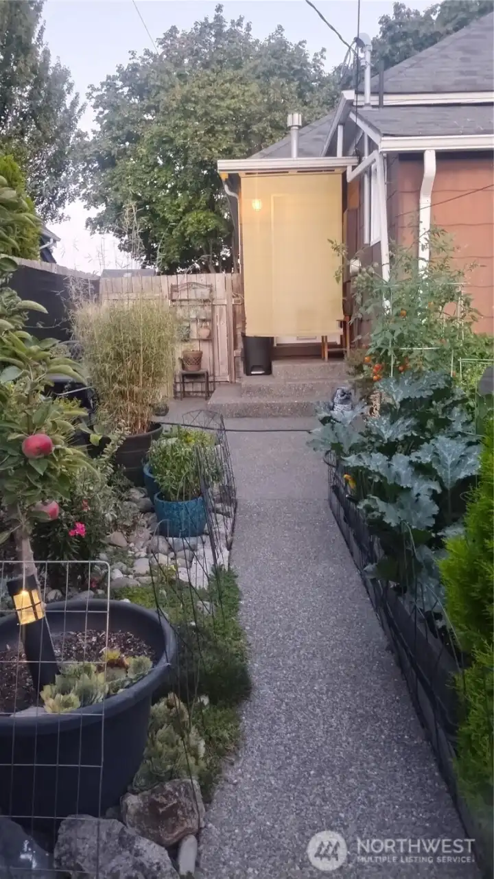 This is a view looking at the rear of the house which has s very large aggregate patio and stairs that lead to the back mudd room. There is a privacy screen hanging in front of the door that is removable.