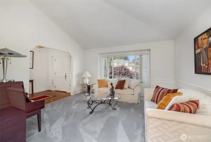 The formal living room impresses with soaring vaulted ceilings and expansive windows that fill the space with natural light.