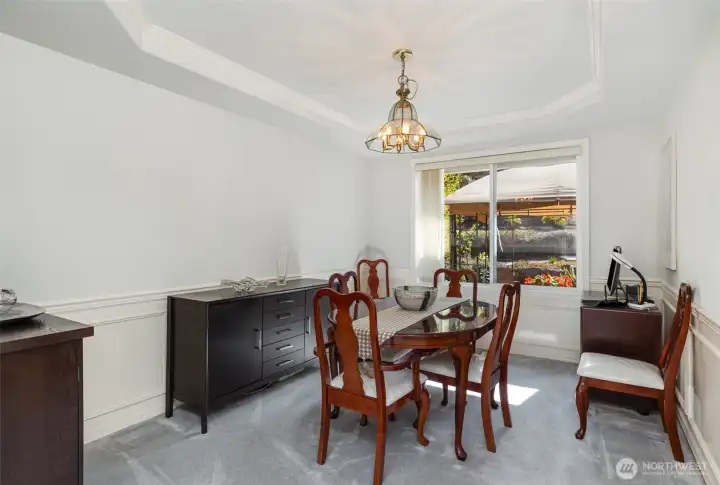 The living area seamlessly flows into the dining room with tray ceilings, creating an open and connected space.