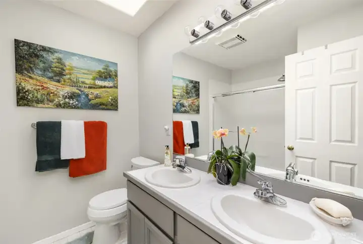Upstairs full guest bathroom offers dual sinks, skylight and plenty of storage below.