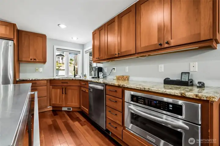 Rich wood cabinetry adds warmth and depth, paired with granite counters that offer durability and beauty. Storage is abundant, with thoughtful cabinet design and generous workspace that keeps everything organized and within easy reach, making the kitchen feel as practical as it is inviting.