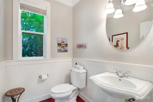 Spacious main floor powder room with wainscoting and pedestal sink.