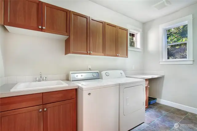 Convenient second floor laundry with utility sink and abundant cabinetry.