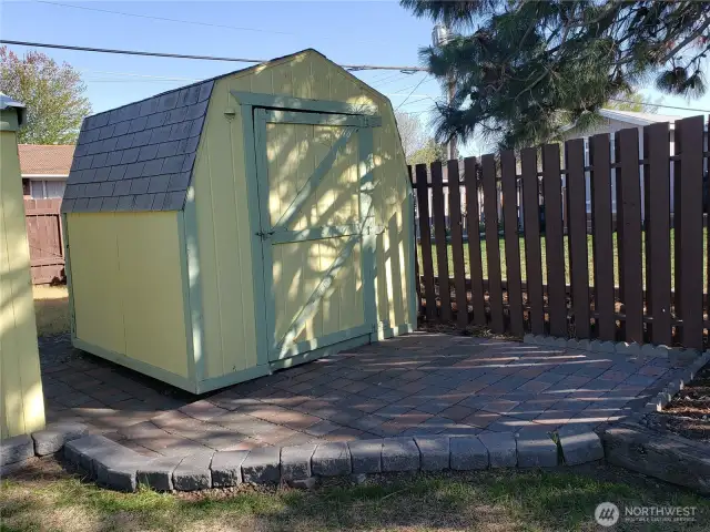 A shed with parking for a small camper behind it in the fully fenced backyard.