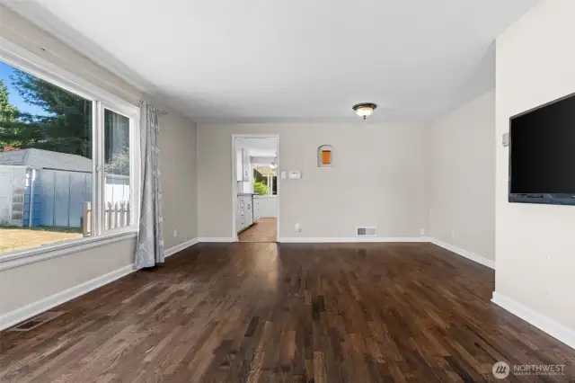 Large picture windows flood the living room with natural light, highlighting its warm and welcoming vibe.