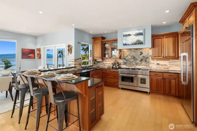 The gourmet kitchen features a Bertazzoni stove, Dacor refrigerator, custom cabinetry, granite countertops with an eating bar