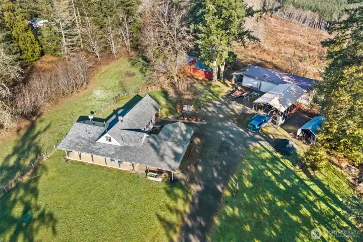 Elevated view capturing the full setup—home, barn, shop, and covered RV parking.